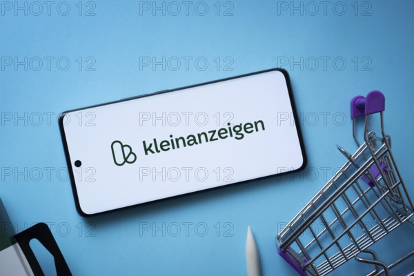 Dhaka, Bangladesh- 03 July 2025: Smartphone displaying Kleinanzeigen logo with shopping cart on a blue background