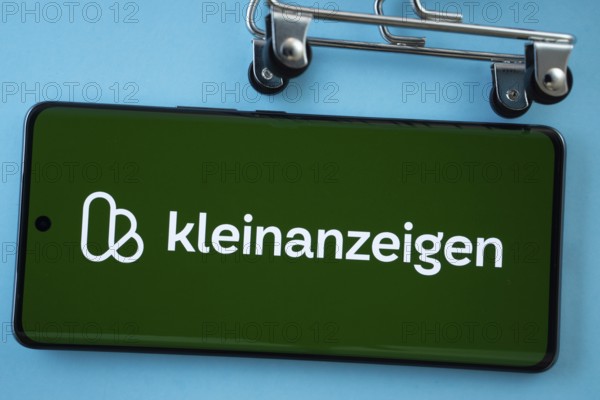 Dhaka, Bangladesh- 03 July 2025: Smartphone screen showing the Kleinanzeigen logo with shopping cart wheels on a blue background