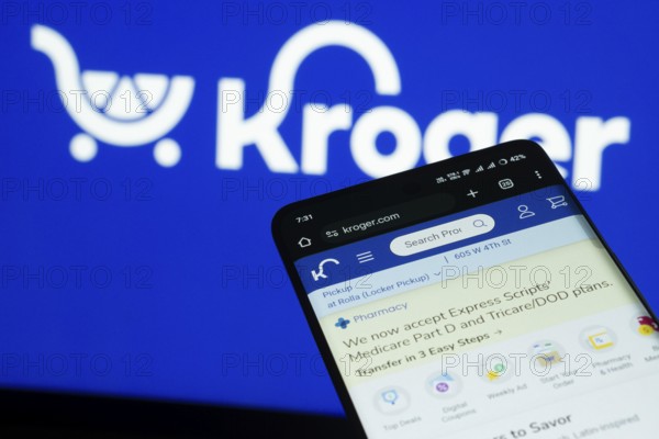 Dhaka, Bangladesh- 03 July 2025: Smartphone displaying Kroger web interface against Kroger logo background