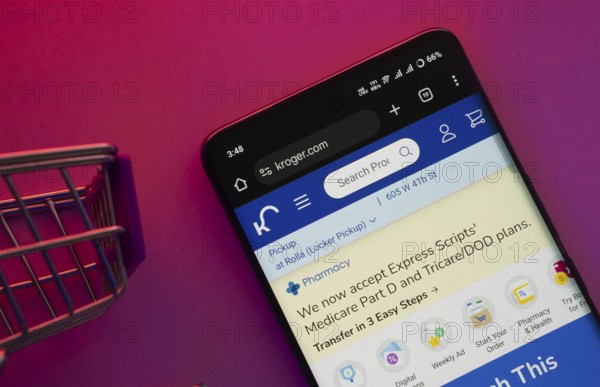 Dhaka, Bangladesh- 23 June 2025: A smartphone displaying the Kroger website with a shopping cart is shown on a vibrant background