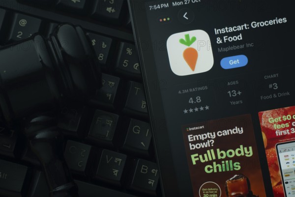 Dhaka, Bangladesh- 28 Oct 2025: An iPad displaying the Instacart app against a judge's gavel and dark keyboard background