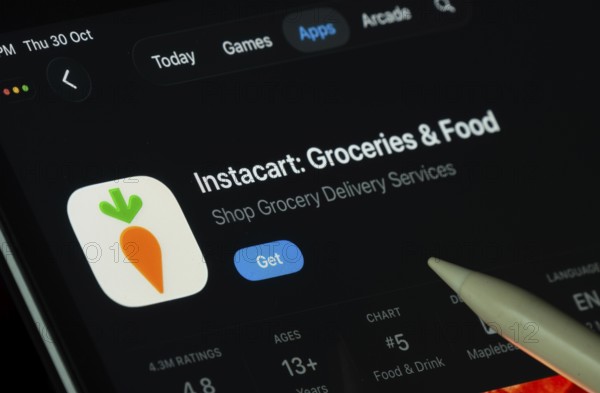 Dhaka, Bangladesh- 30 Oct 2025: Instacart app displayed on a iPad screen in dark mode with a digital pen pointing at it