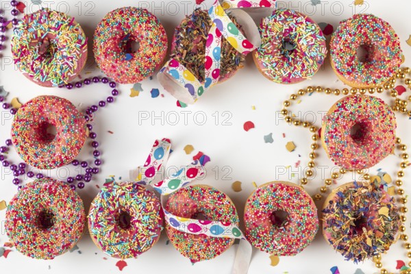 Donuts with sprinkles and confetti surrounded by streamers and strings of pearls on a bright background