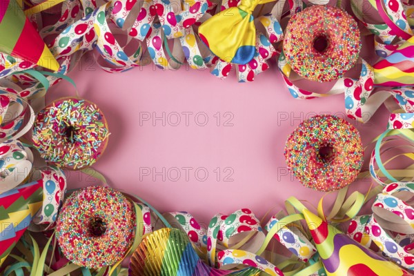 Colourful donuts and streamers with party hats frame a pink area, carnival