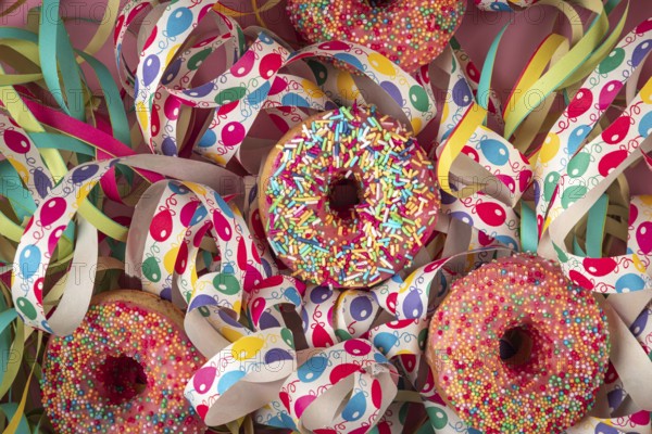 Colourful donuts nestled in colorful streamers that create a festive atmosphere, carnival