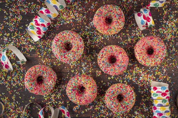 Donuts with colorful sprinkles and confetti on table, carnival