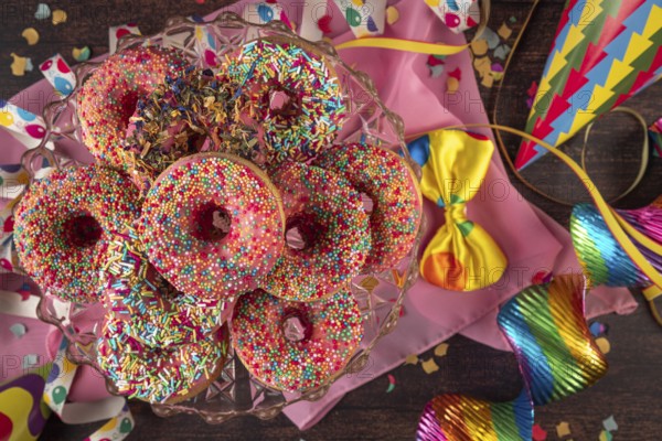 Colourful donuts with party decorations such as streamers, bow and confetti, carnival