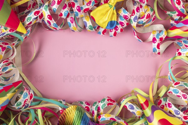 Party hats and colorful streamers frame a pink background, Mardi Gras
