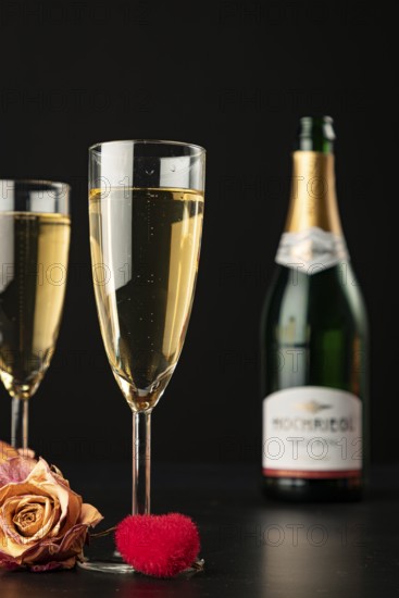 Two glasses on a black background with roses and a red heart