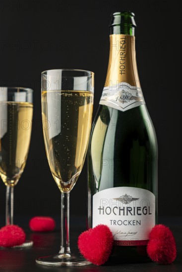 Close-up of champagne bottle and glasses with red hearts on black background