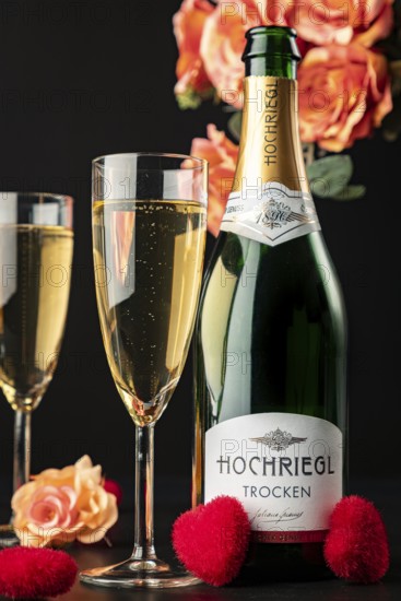 Hochriegl champagne bottle and filled glasses surrounded by roses and red hearts