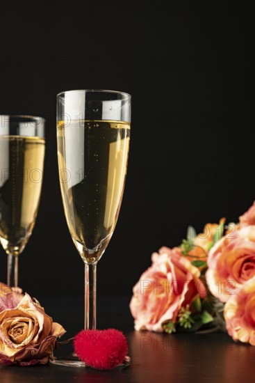 Filled champagne glasses with roses and heart, dark background, Valentine's Day