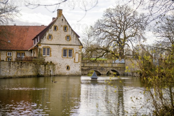 An old moated castle in Melle Haus Sondermühlen with bridge, surrounded by a large pond and trees Melle, Lower Saxony, Germany
