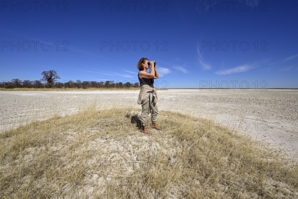 Tourist observes animals through binoculars near the Baines Baobabs, Kudiakam Pan, Nxai-Pan National Park, near Gweta, Central District, Botswana