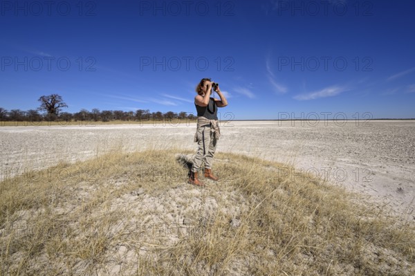 Tourist observes animals through binoculars near the Baines Baobabs, Nxai-Pan National Park, near Gweta, Central District, Botswana