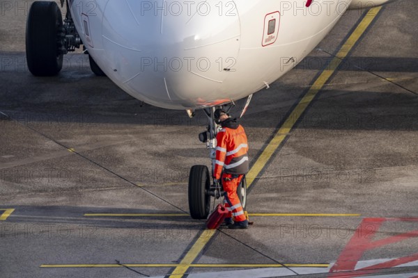 Ground crew positions brake blocks on the chassis, after stopping at the parking position, at the terminal, gate, at the Cologne/Bonn airport passenger bridge, CGN, North Rhine-Westphalia, Germany