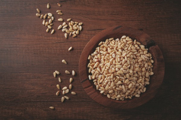 Peeled pine nuts, in a wooden bowl, on a wooden table, close-up, no people