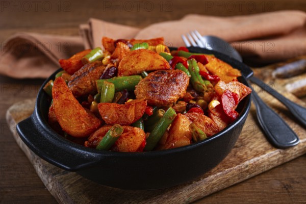 Steakhouse pfanne, fried potato slices, with meatballs, and vegetable mixture, on a black plate