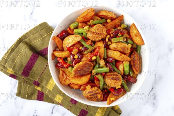 Steakhouse pfanne, fried potato slices, with meatballs, and vegetable mixture, on a white plate