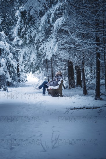 A person sitting on a bench in a snowy forest, Broomfield, Black Forest, Germany