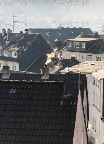 Smoke plume from a chimney over densely built residential area in the evening light, wintry city scene, Wuppertal, Germany