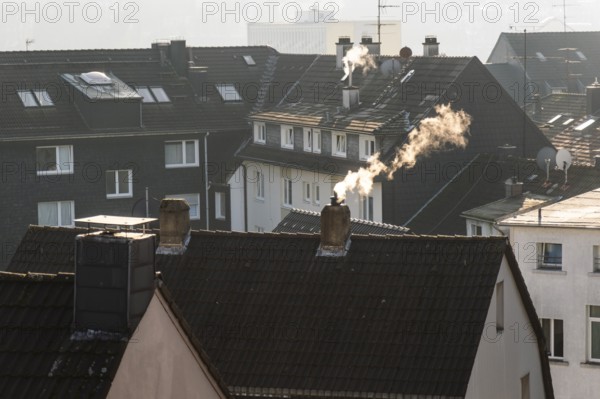 Smoke plume from a chimney over densely built residential area in the evening light, wintry city scene, Wuppertal, Germany