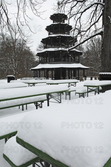 Winter in the English Garden, snow-covered beer garden tables and benches, Chinese Tower, Munich, Bavaria, Germany
