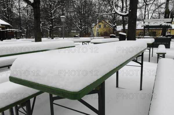 Winter in the English Garden, snow-covered beer garden tables and benches, Munich, Bavaria, Germany