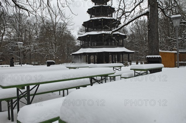Winter in the English Garden, snow-covered beer garden tables and benches, Chinese Tower, Munich, Bavaria, Germany
