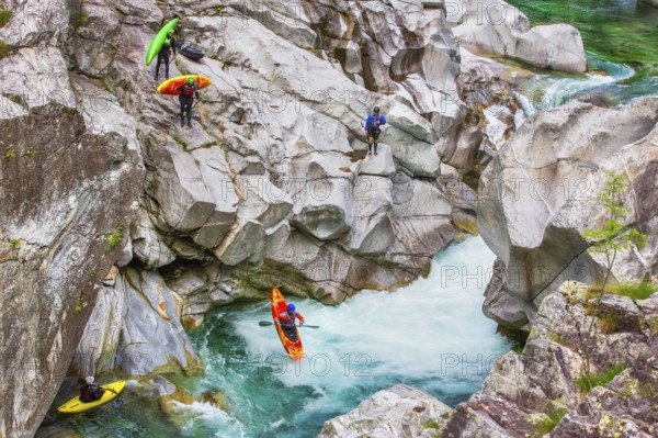 Group of tourists canyoning with canoes, jumping from the rocks of the Verzasca River in summer, Verzasca Valley, Ticino Canton, Switzerland