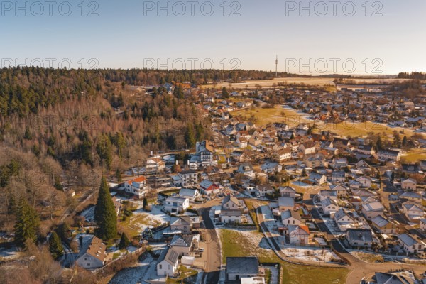A village in the winter countryside, surrounded by forest and fields, with a distant antenna tower, Hallwangen, Freudenstadt district, Germany