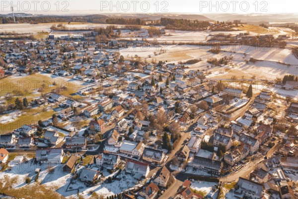 Wide settlement in winter with snow-covered roofs and fields in sunlight from an aerial perspective, Hallwangen, Freudenstadt district, Germany