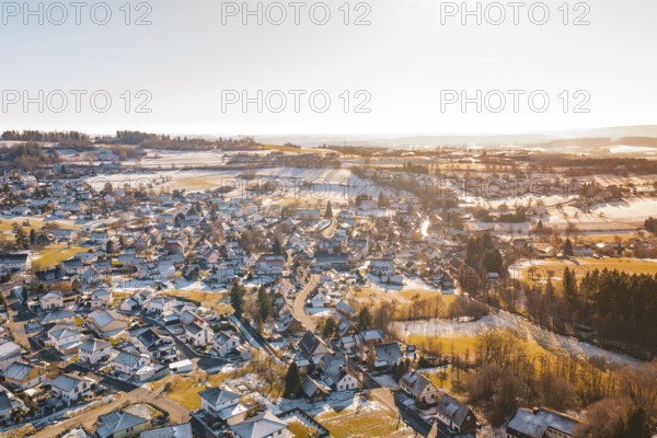 A wintry hilly landscape with a village under snow-covered roofs, surrounded by fields, Hallwangen, Freudenstadt district, Germany