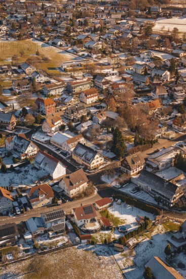 Bird's-eye view of city with snow-covered roofs in winter at sunset, Hallwangen, Freudenstadt district, Germany