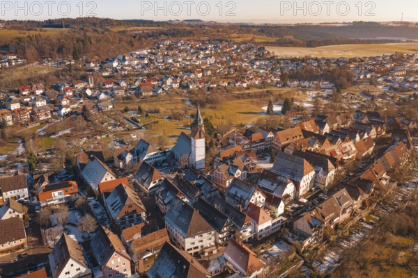 Aerial view of a town with church and buildings in evening light, surrounded by hills and fields, Dornstetten, Freudenstadt district, Germany