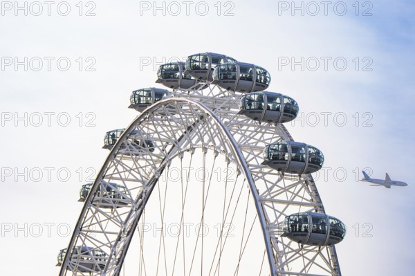 Ferris wheel with an airplane in the blue sky in the background, London Eye, London, United Kingdom