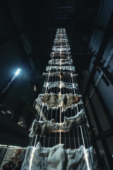 Tall vertical installation with metal and fur elements in a dark room, Tate Modern of Art, Lodon, United Kingdom
