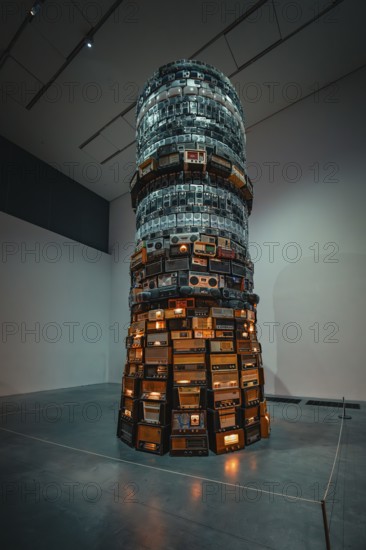 A tall tower of stacked radios with illuminated elements in the museum, Tate Modern of Art, Lodon, United Kingdom