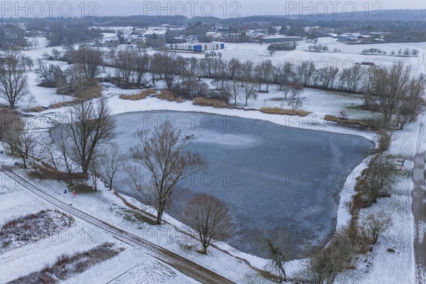 Small lake in snowy landscape with village background and bare trees, Empfingen, Freudenstadt district, Germany
