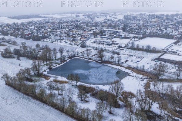 Snowy village panorama with central lake and surrounding fields from the air, Empfingen, Freudenstadt district, Germany
