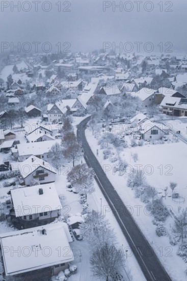 Snowy village with snow-covered houses and roads under cloudy sky, Schopfloch, Freudenstadt district, Germany