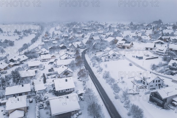 Aerial view of a snowy village with snow-covered buildings and cloudy sky, Schopfloch, Freudenstadt district, Germany