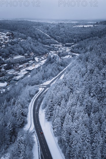 Snowy road through a forest, quiet winter landscape with lonely car, Altensteig, Calw district, Germany