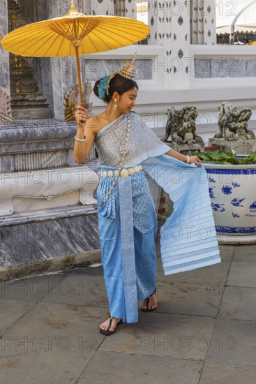 Young woman wearing a parasol in traditional clothing presents herself for the photographers, Wat Arun Buddhist temple, Bangkok, Thailand's metropolis, Thailand