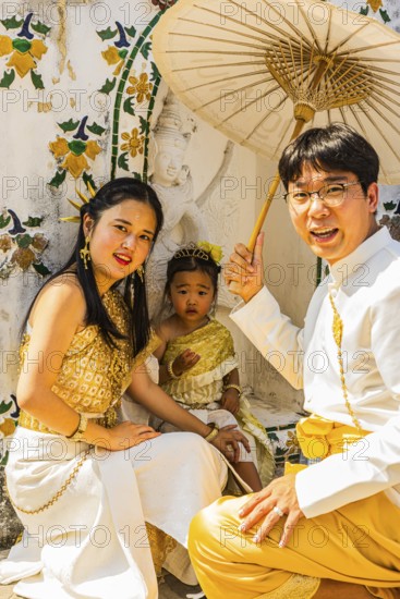 Young family with toddler and parasol in traditional clothing present themselves for the photographers, Buddhist temple Wat Arun, Bangkok, Thailand's metropolis, Thailand