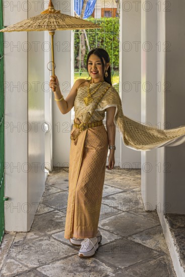 Young woman wearing a parasol in traditional clothing presents herself for the photographers, Wat Arun Buddhist temple, Bangkok, Thailand's metropolis, Thailand