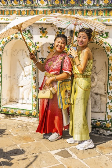 Young woman with umbrellas in traditional clothing present themselves for the photographers, Wat Arun Buddhist temple, Bangkok, Thailand's metropolis, Thailand