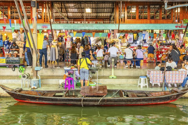 Wooden boat on the Damneon Saduak floating markets channel, behind shops and restaurant, near Bangkok, Ratchaburi district, Thailand