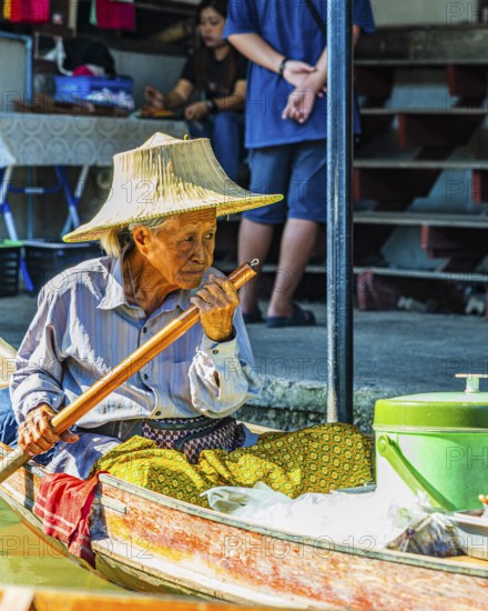 Old woman with her wooden boat on the Damneon Saduak floating markets channel, near Bangkok, Ratchaburi district, Thailand