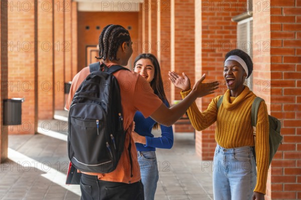 Diverse young students are happily greeting each other while walking along a brick wall corridor on a university campus, sharing a moment of friendship and connection